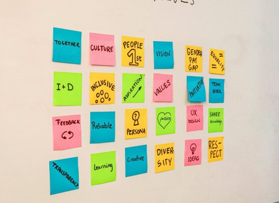 Colorful sticky notes displaying company values on a white board, emphasizing teamwork and innovation.
