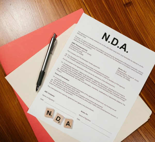A close-up view of an NDA document, pen, and files on a wooden surface, perfect for legal or business themes.